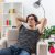 young man in casual clothes happy and positive relaxing spending weekend sitting on the chair in light living room